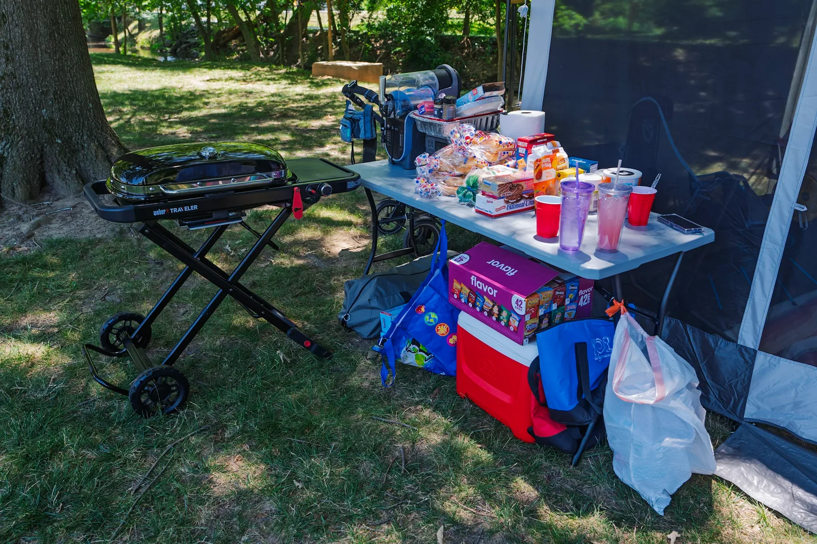 Our full camp spread: grill, a table of food and drinks, and coolers