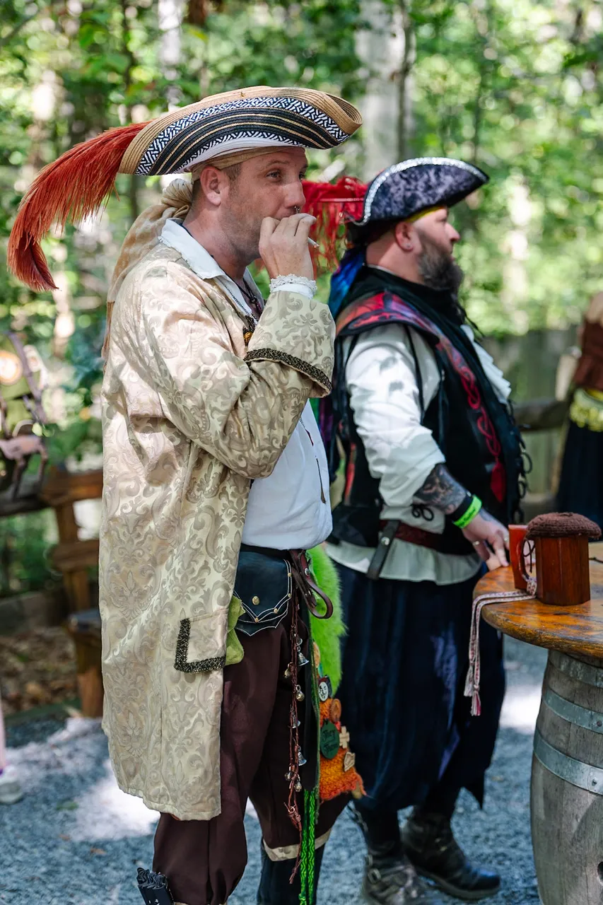 Two elaborately dressed pirates sharing a moment at a barrel table